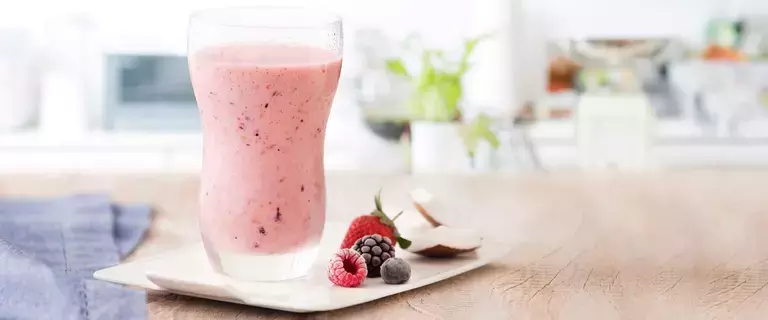 fotografía y tonos de rosa y blanco de un banco beige visto de frente, contiene un vaso transparente con la bebida de frutos rojos y al lado contiene frutos del bosque. fotografía y tonos de rosa y blanco de un banco beige visto de frente, contiene un vaso transparente con la bebida de frutos rojos y al lado contiene frutos del bosque.