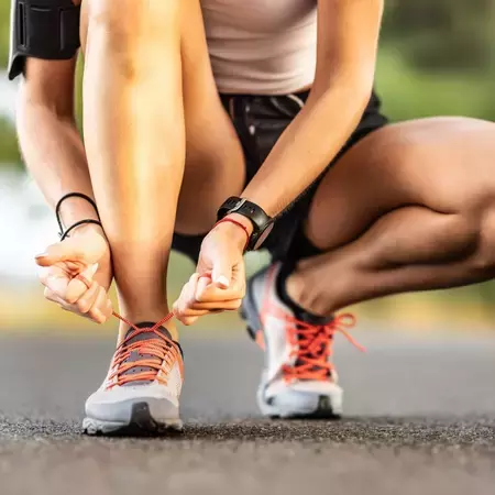 Person bent down tying their shoelaces