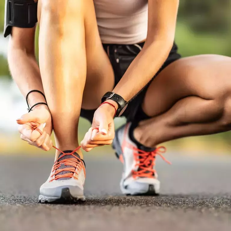 Person bent down tying their shoelaces