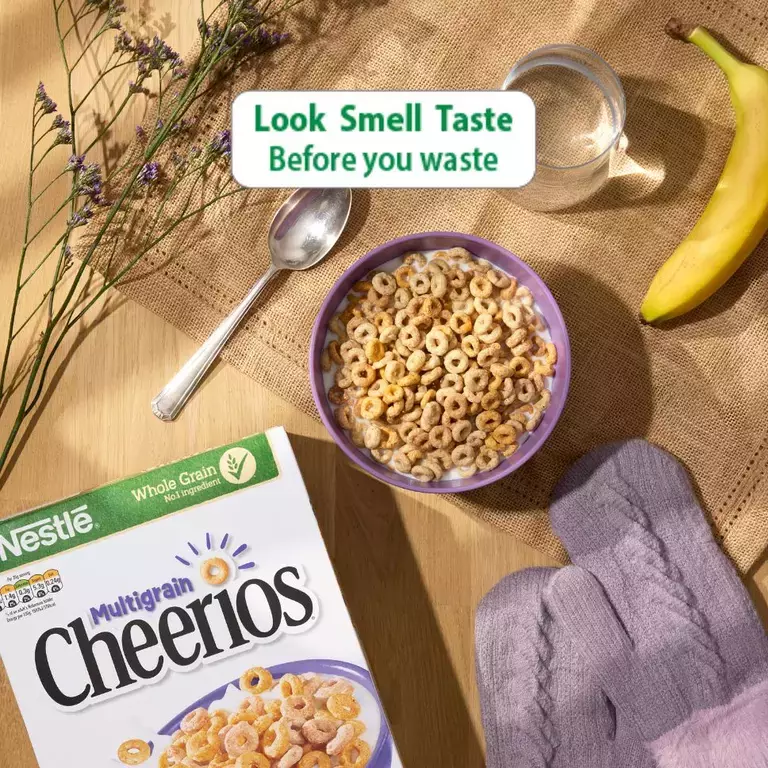 A bowl of cheerios next to a box of Cheerios and a banana. The logo with copy Look Smell Taste before you waste above it