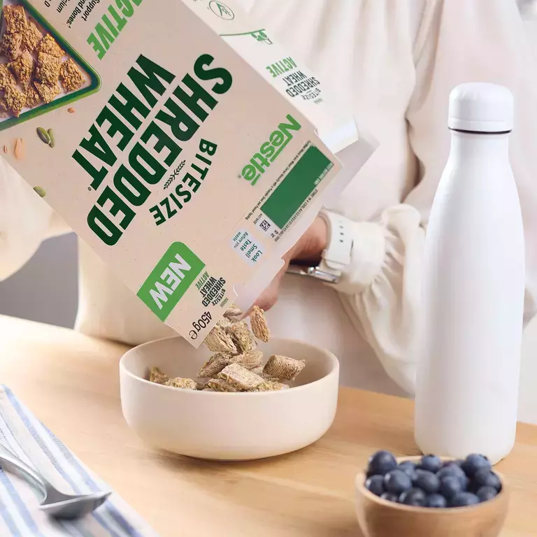 A person pouring Shredded Wheat Active cereal into a bowl