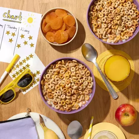 Bowls of Cheerios on the table with a pair of sunglasses, fruit and a star chart